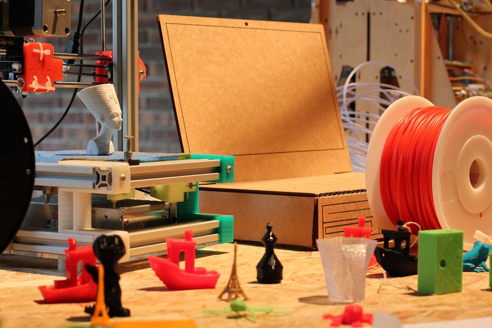 des objets imprimés en 3D sur un établi, devant une imprimante 3D