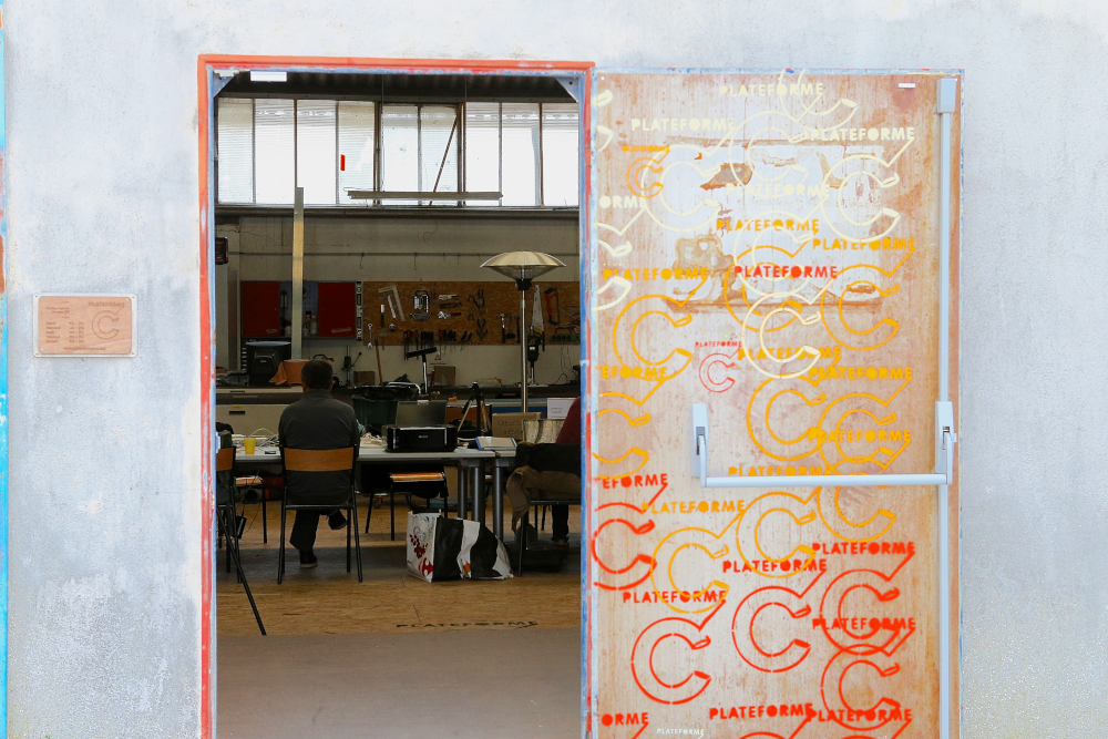 porte ouverte sur des ateliers où des personnes travaillent