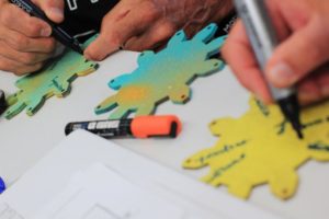 gros plan sur des mains dessinant sur des objets découpés