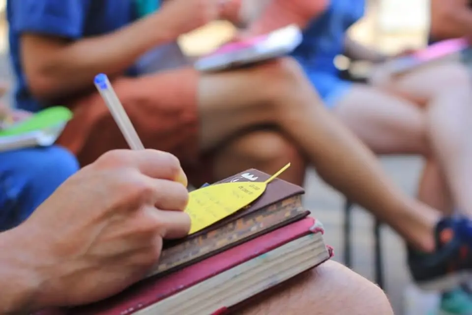 une personne prend des notes sur un ouvrage, détail d'un main tenant un crayon