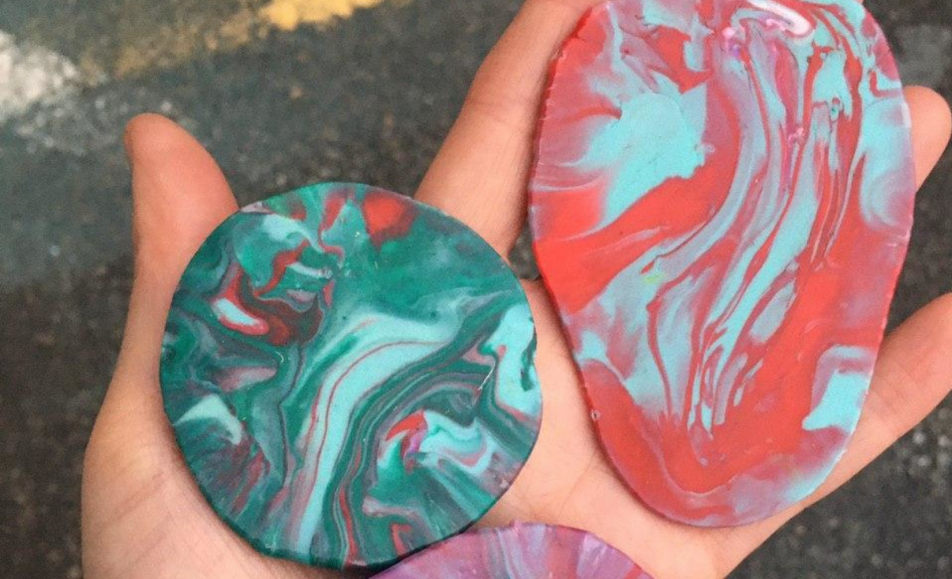 Détails d'expérimentations palsstiques : des galets de plastiques fondu posés dans la paume d'une main