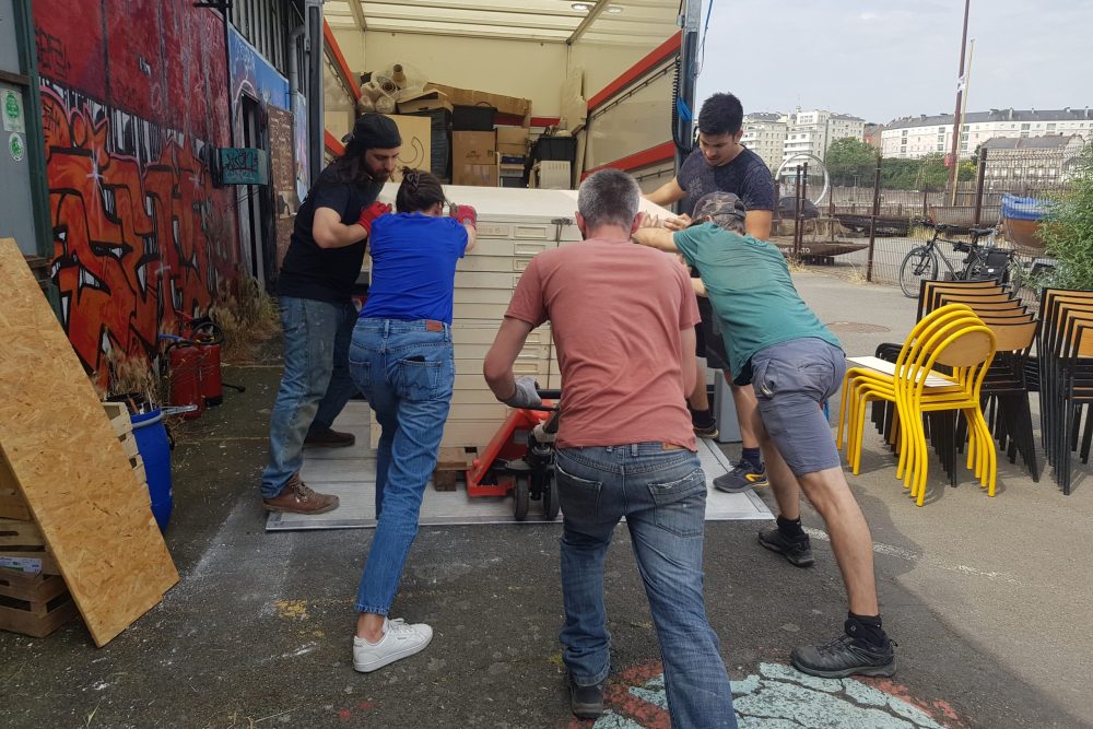 des perosnne schargent une machines dans un camion de déménagement