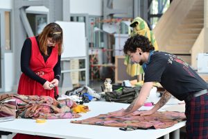 Deux personnes étendent des tissus sur une grande table