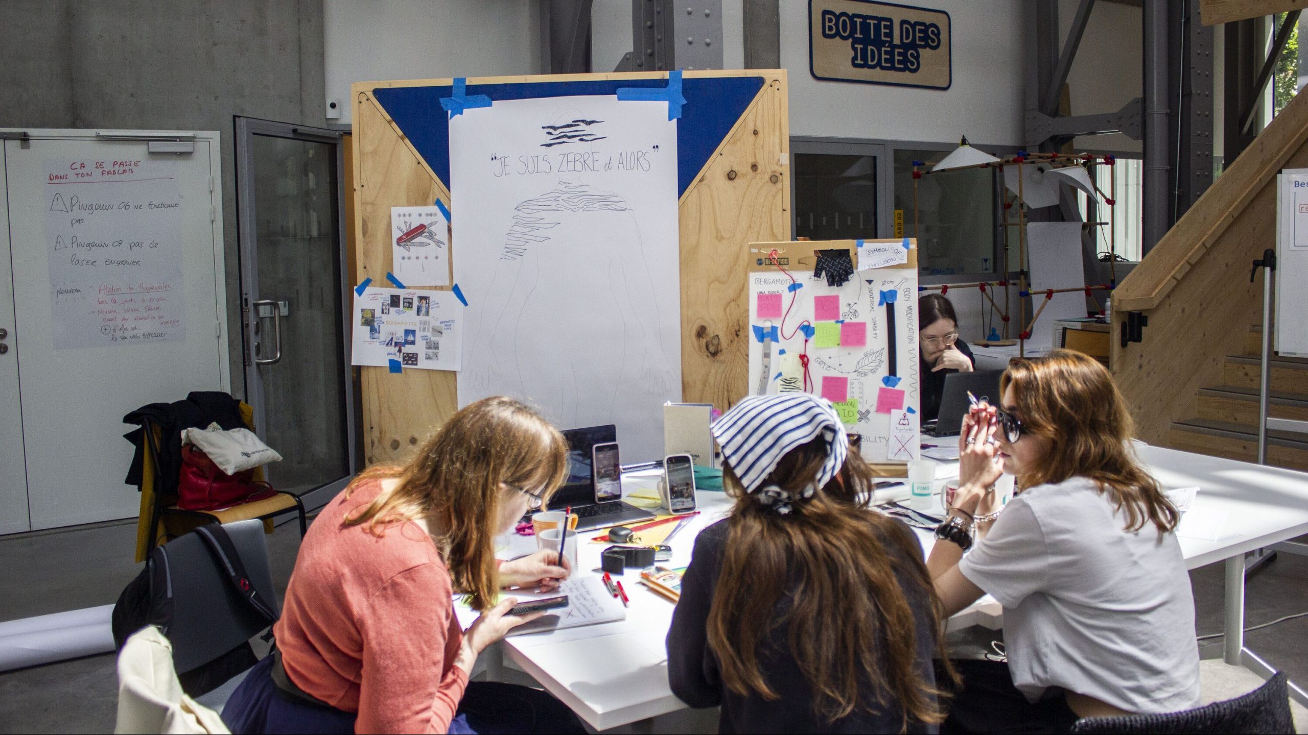 Photo de trois femmes autour d'une table avec des dessins et moodboards
