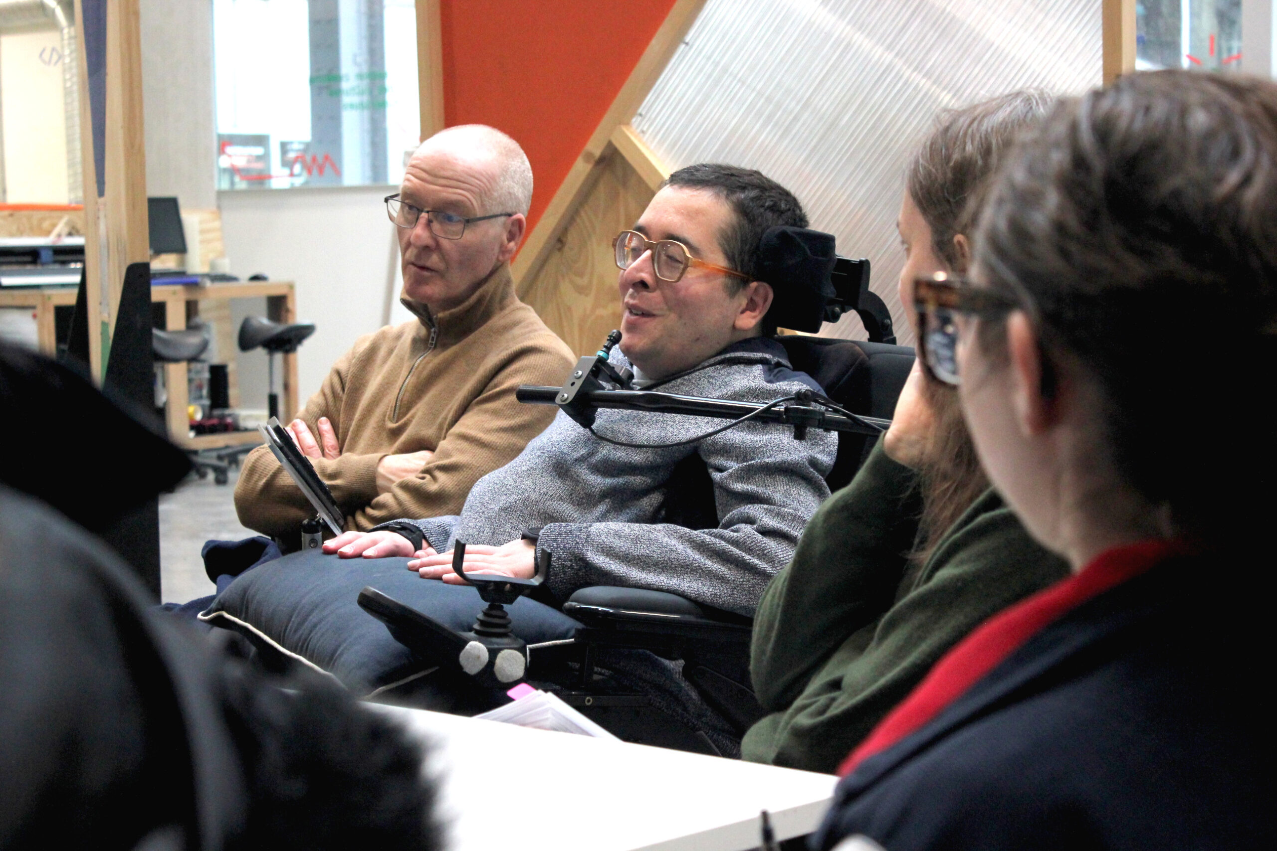IMG_2582R Photo de trois personnes autour d'une table, deux femmes et un homme, l'un des hommes est en fauteuil roulant