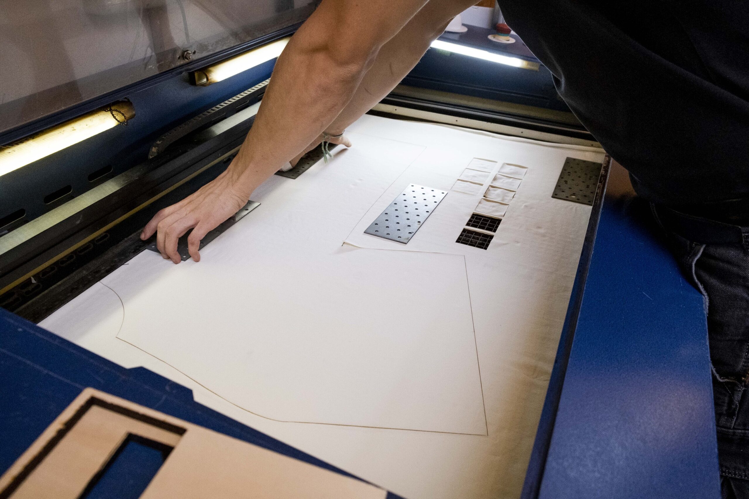 Photo d'une personne qui découpe du coton avec une machine de découpe laser, la forme découpée ressemble à un t-shirt